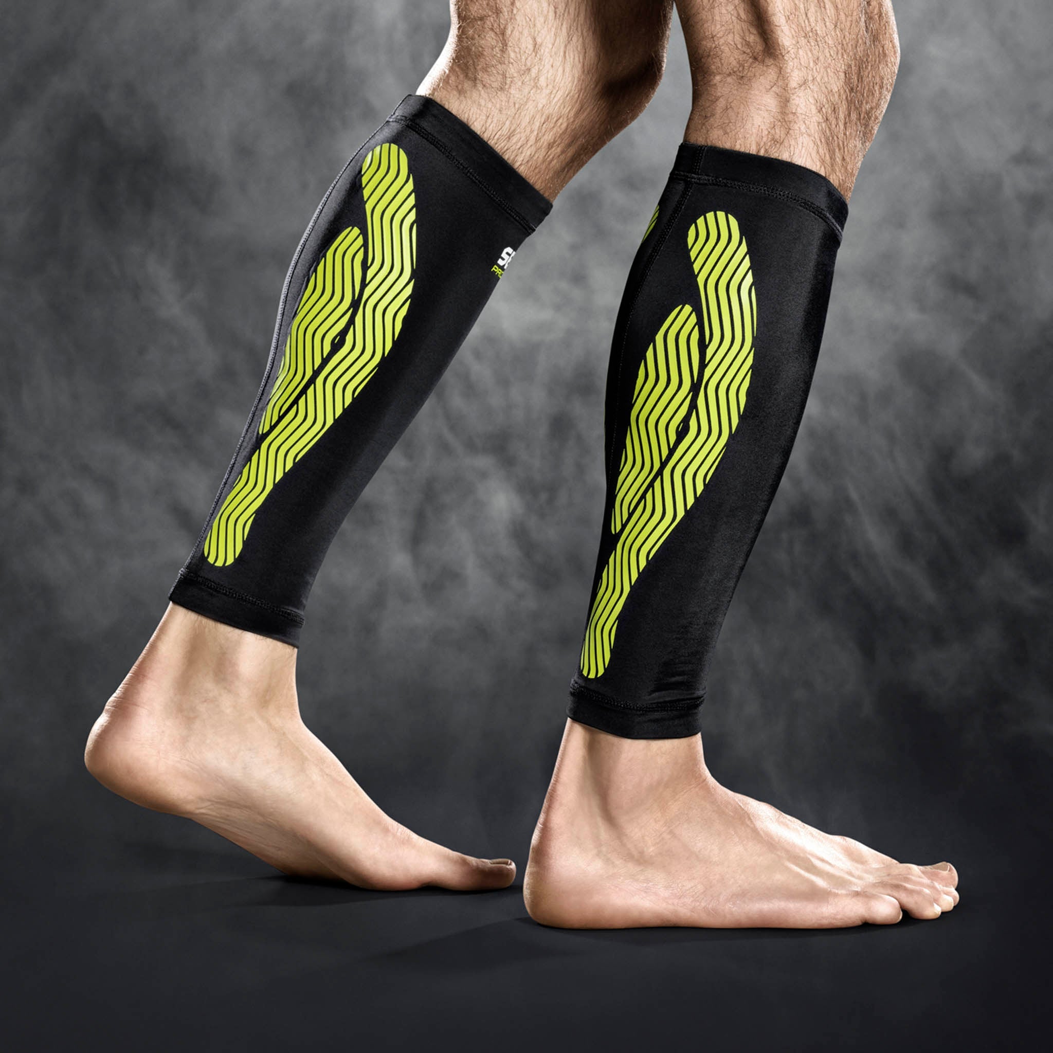 Svart og grønn Compression Calf 6150 sportsstøtte brukt på begge legger, modellvisning.