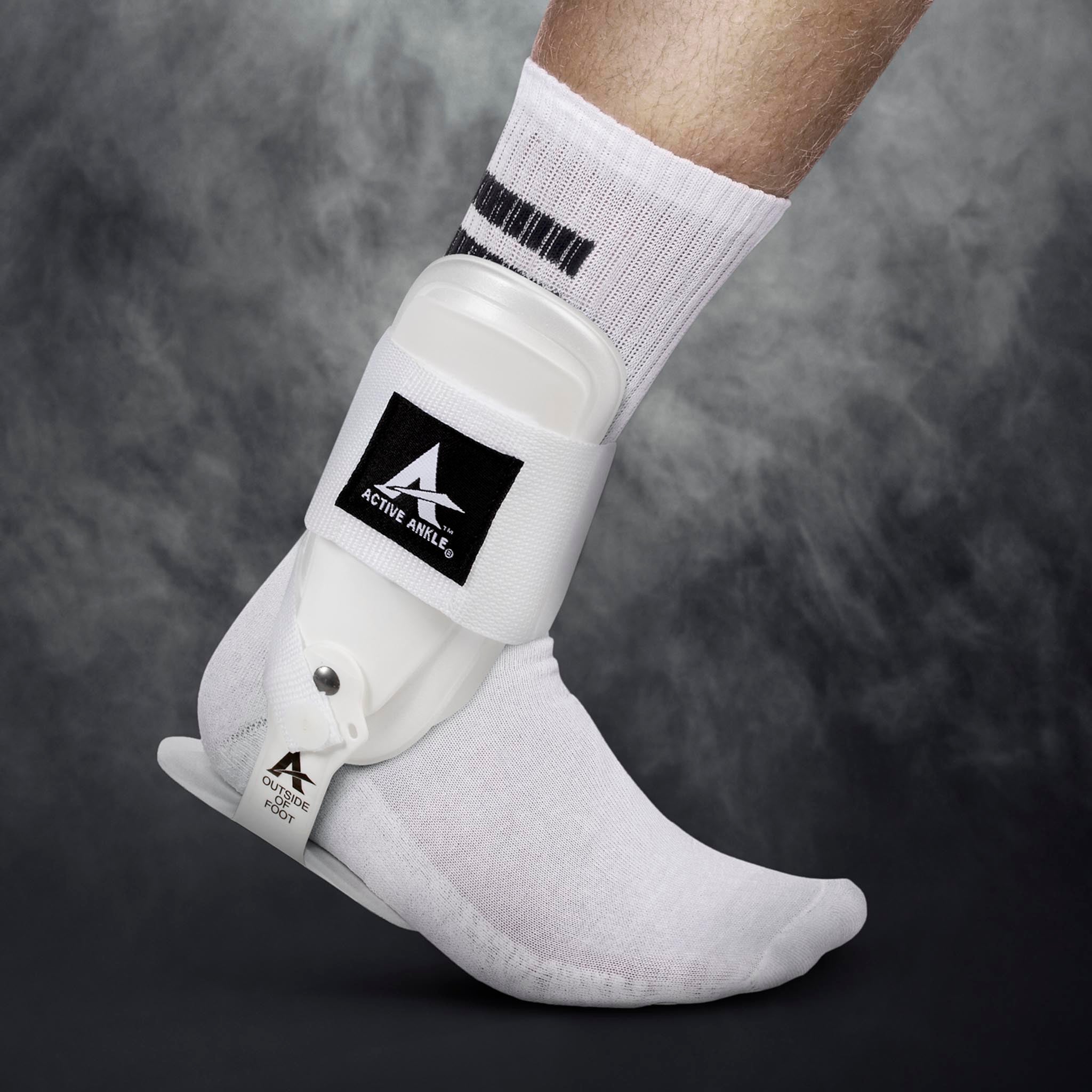 Hvit Active Ankle T-2 sportsstøtte på en fotballspillers fot, modellbilde.
