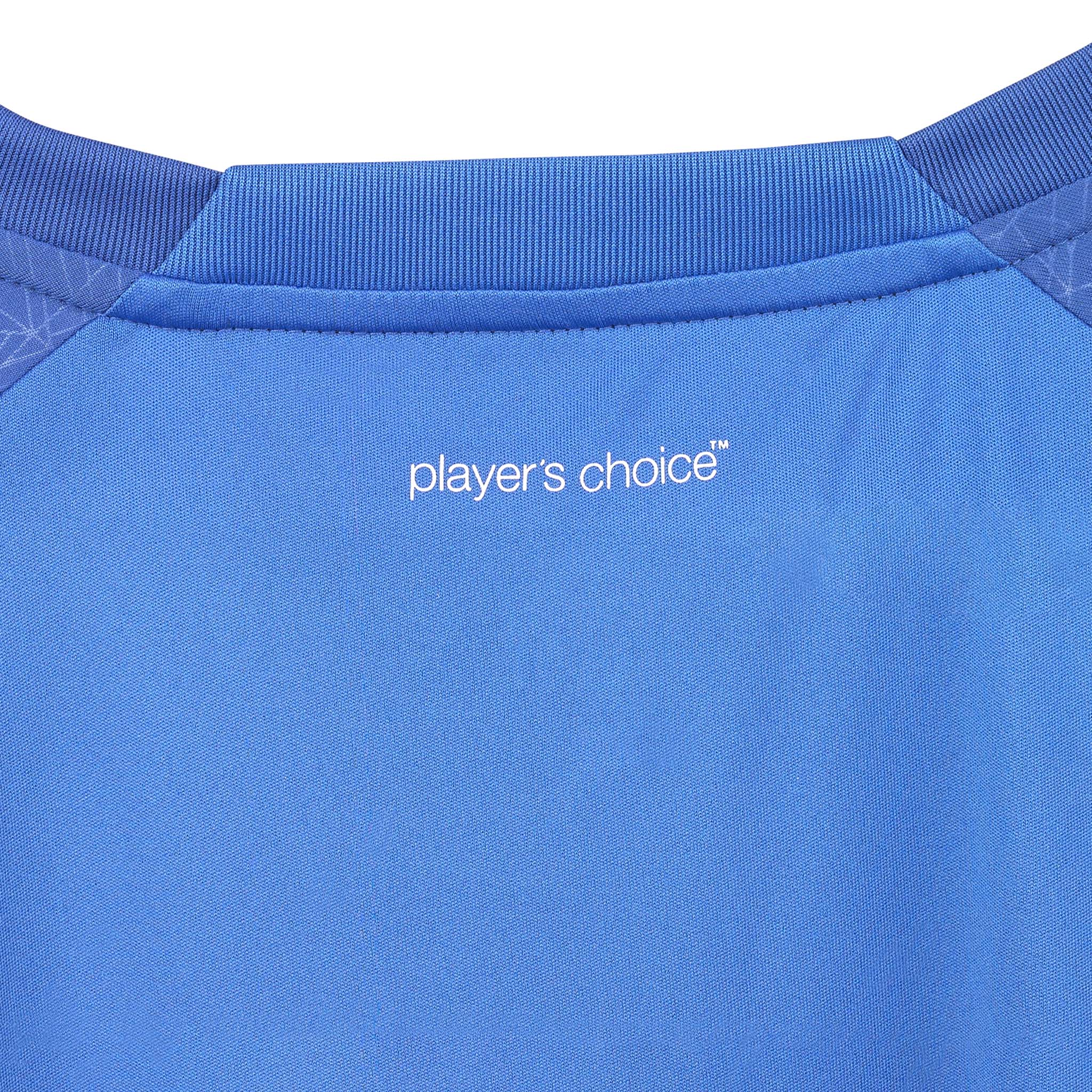 Nærbilde av blå Player shirt S/S Spain woman v25, Match & Training wear, hvit "player's choice"-logo og kragedetalj.