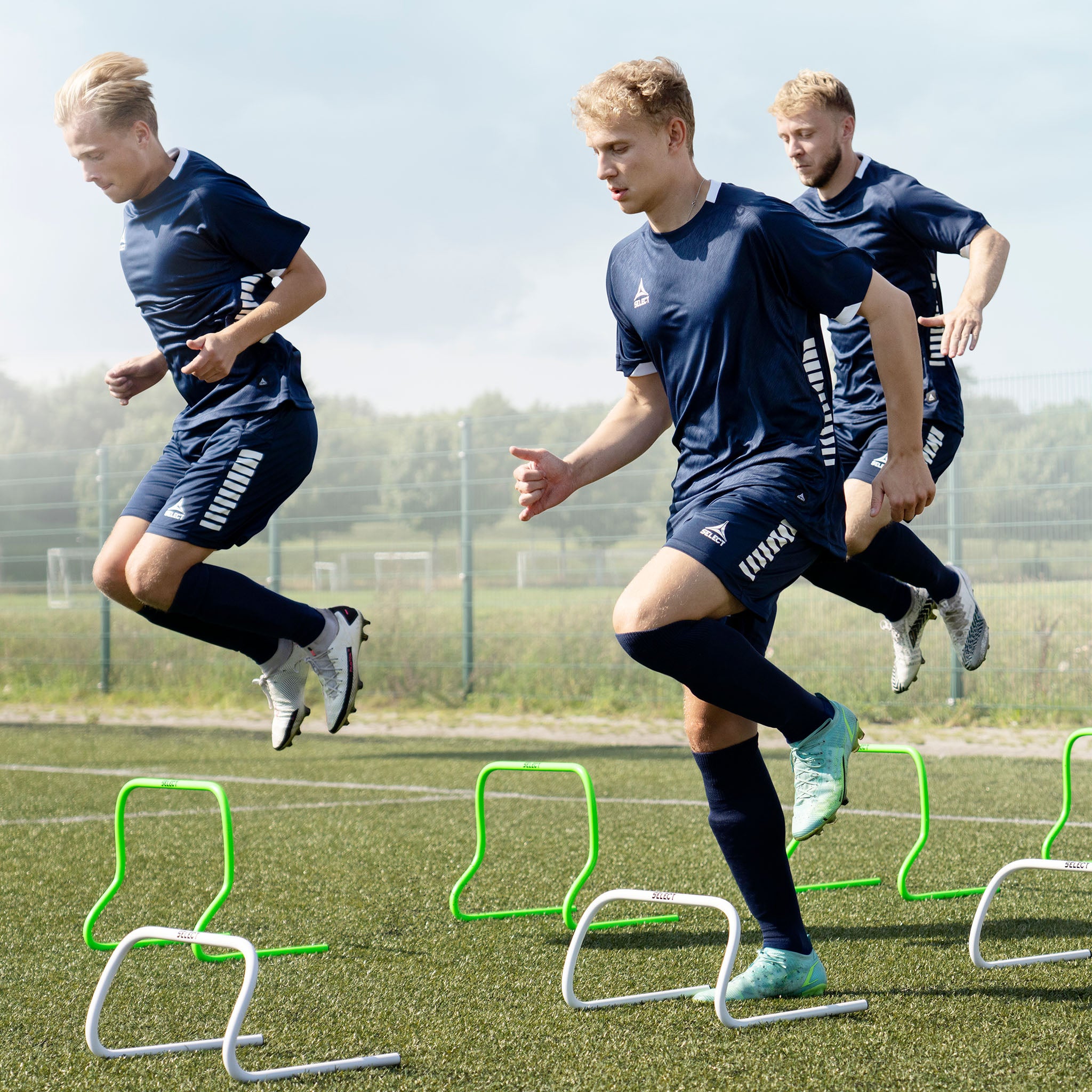 Forsidebilde av fotballspillere som bruker grønt Training hurdle treningsutstyr på en bane.